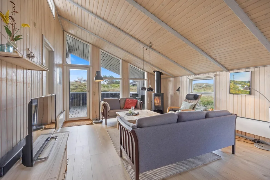 Una sala luminosa con asientos, grandes ventanas y una estufa de leña.