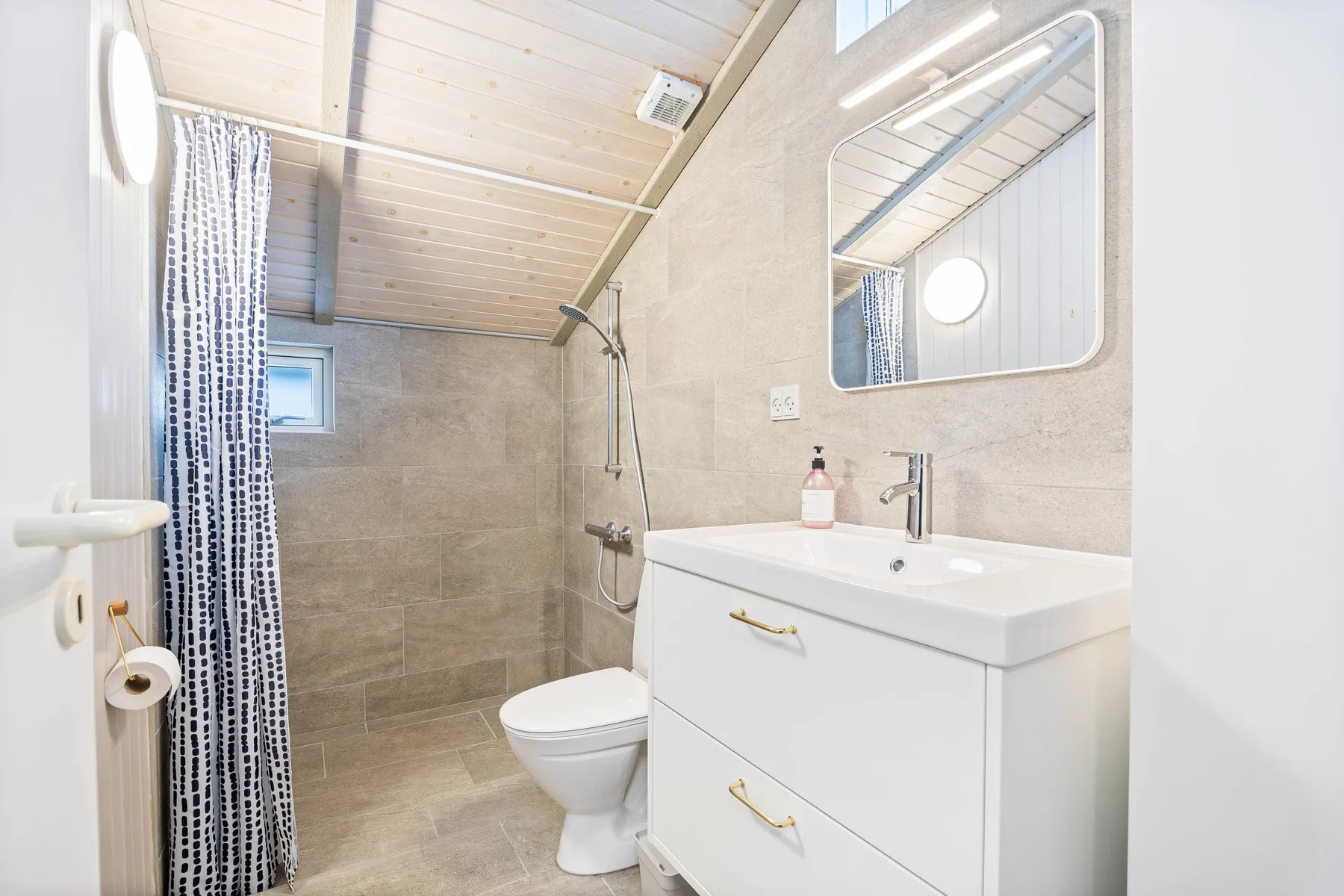 Un baño con un mueble blanco, espejo y cortina de ducha.