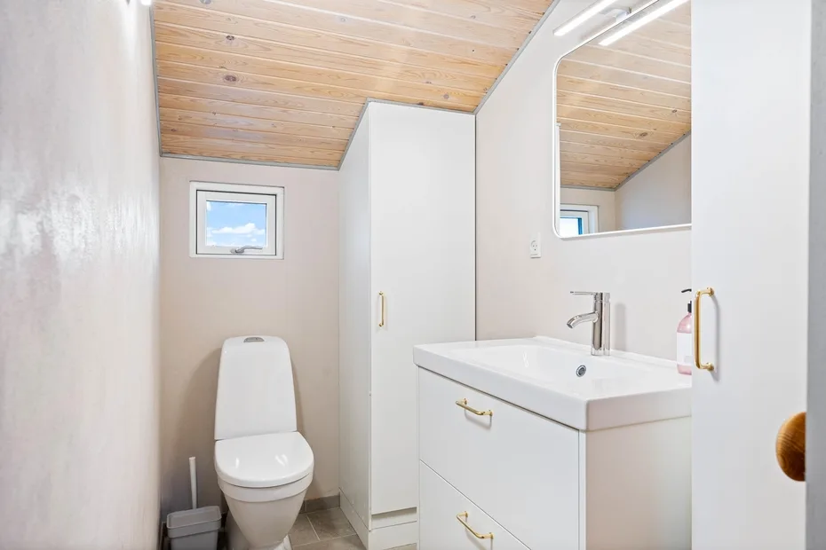 Un baño luminoso con inodoro, mueble de lavabo y espejo grande.