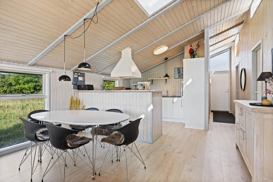 Una luminosa cocina-comedor de planta abierta, con una mesa redonda y lámparas colgantes.