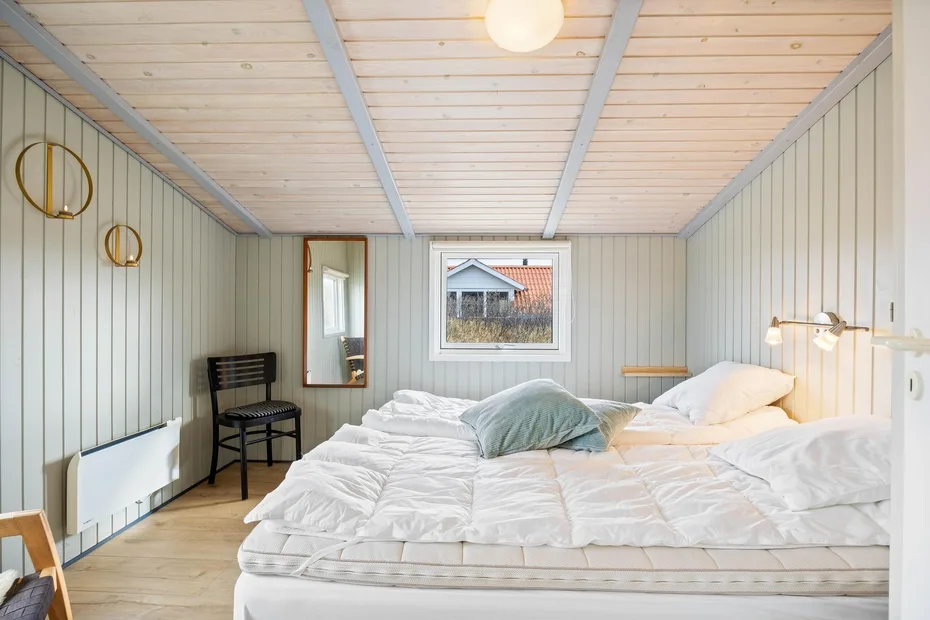 Un dormitorio luminoso con una cama grande, ropa de cama blanca y una ventana.