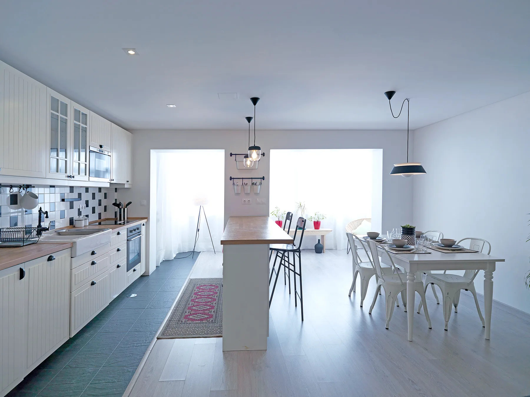 A bright kitchen and dining area with a central island and a table by the windows.