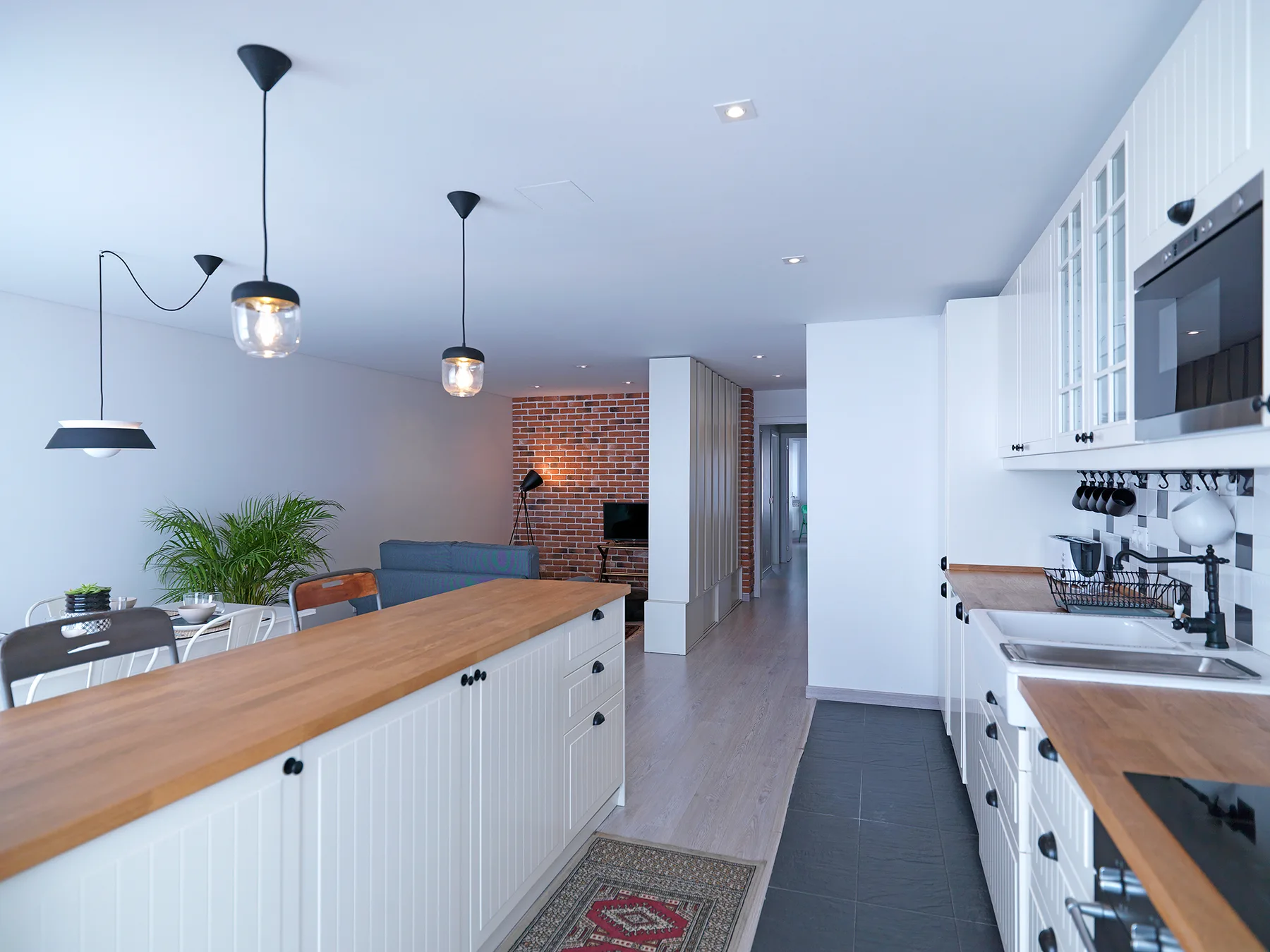 A modern kitchen with a long wooden island and white cabinetry.