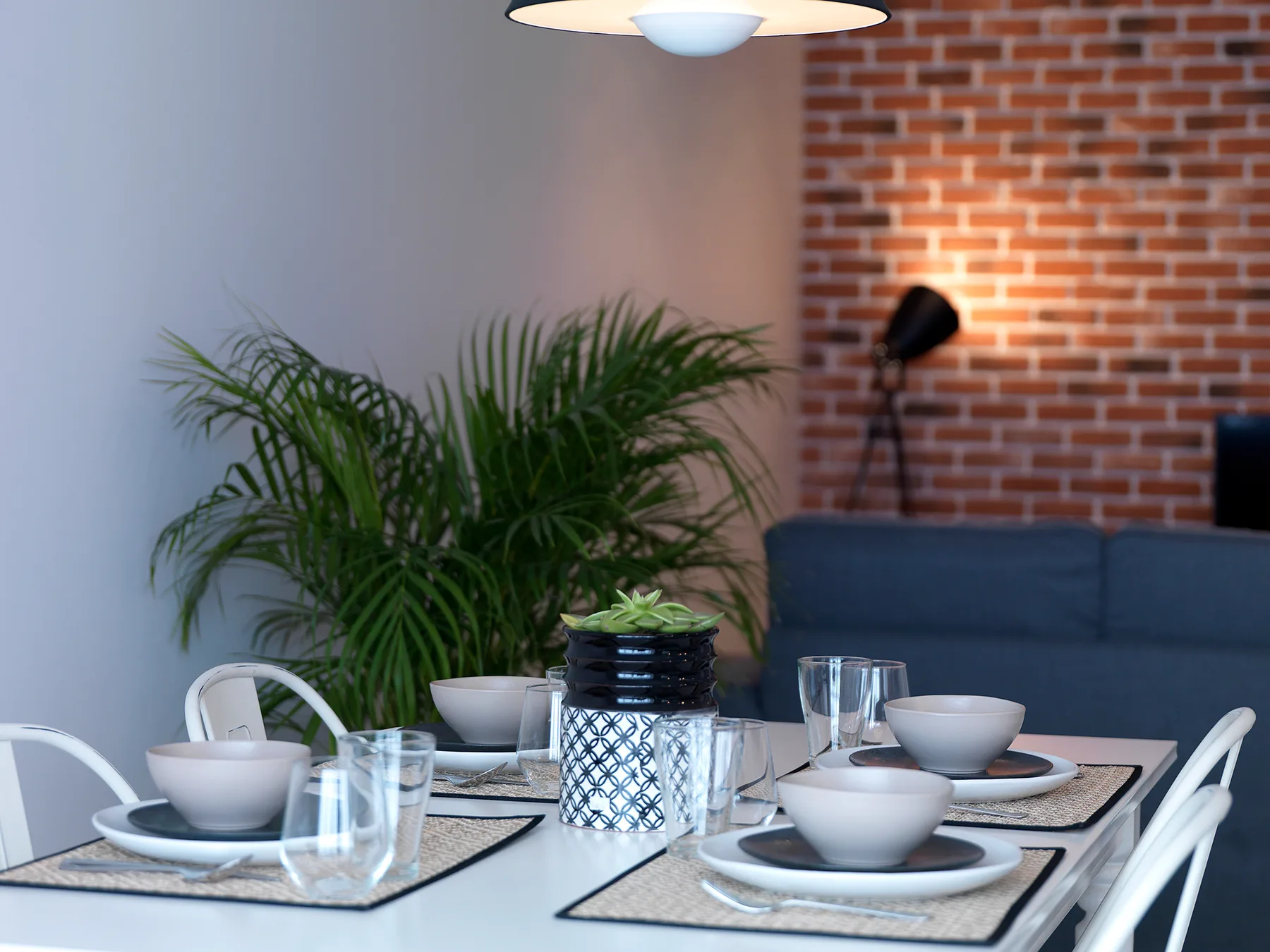 A dining area with a set table and a leafy potted plant.