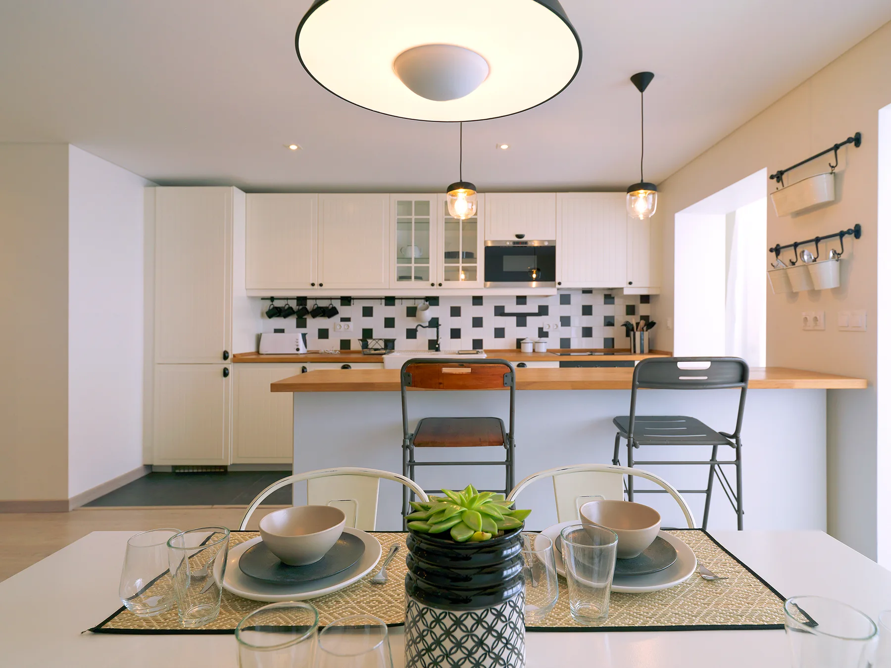 A kitchen with a dining table set with dishes and a small plant.