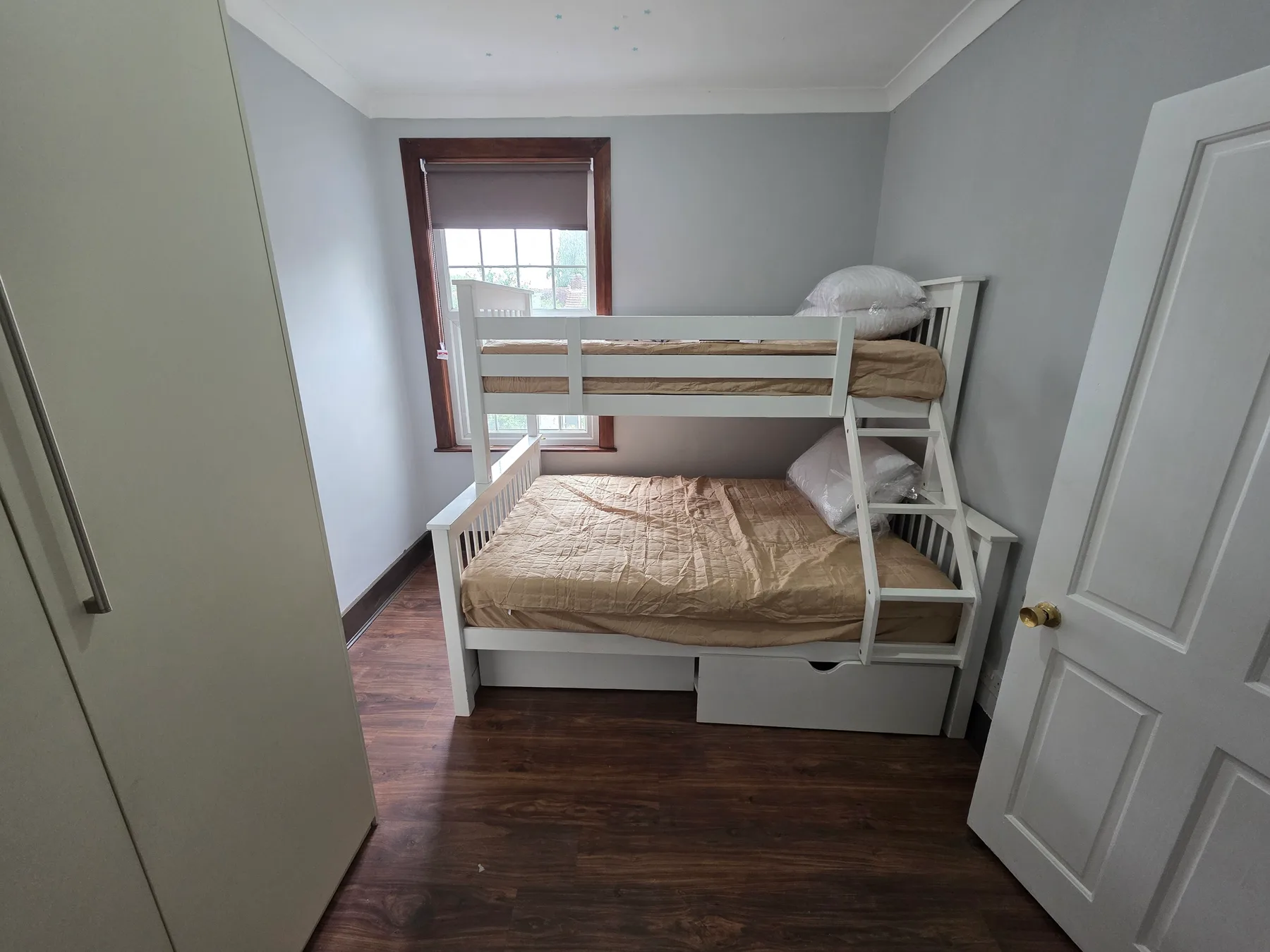 A bedroom with a white bunk bed and a window.