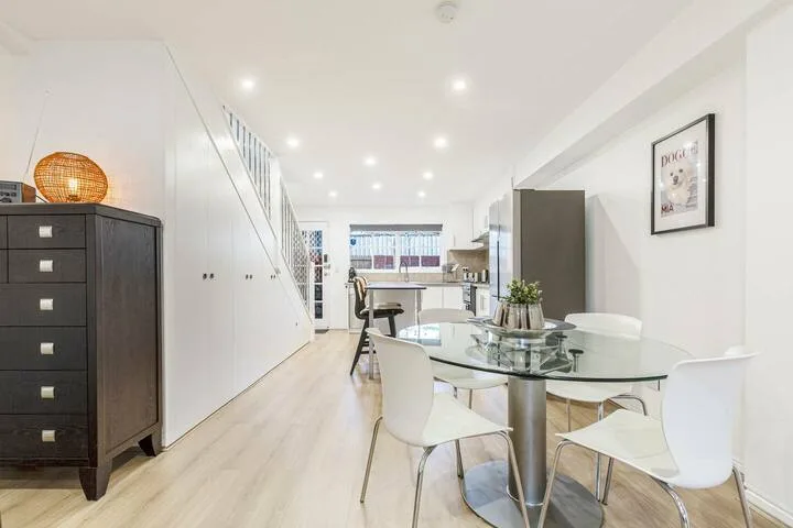 A bright dining area with a glass table and white seating.