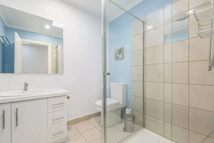 A bathroom with a vanity beside a glass-enclosed shower.