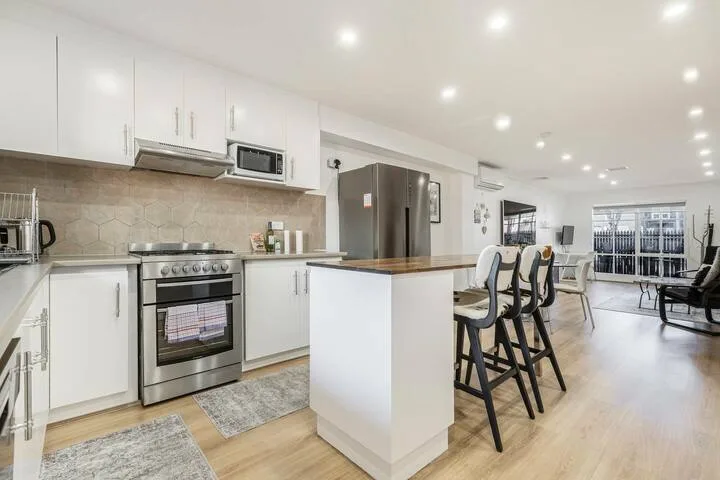 A bright open-plan kitchen and dining area with an island and bar seating.