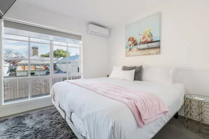 A bright bedroom with a neatly made bed and large sliding glass doors.
