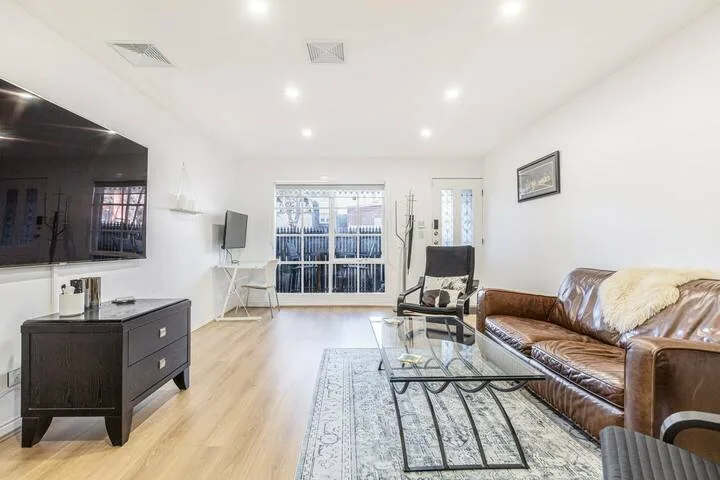 A bright living room with leather seating and a glass coffee table.