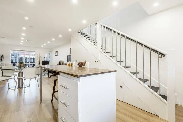 A bright open-plan kitchen and dining area with an island and staircase.