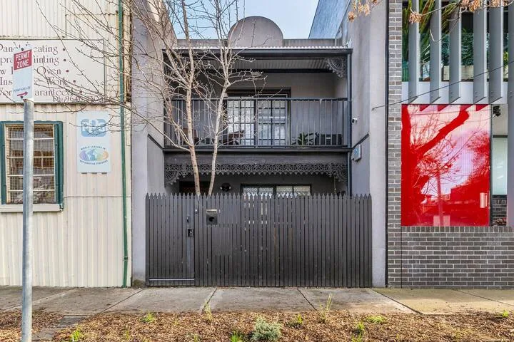 A street-facing building with a dark metal gate and balconies above.