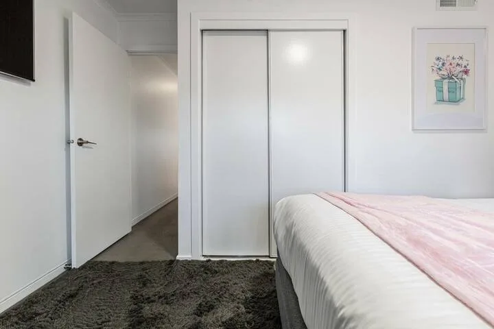A bedroom with a bed, a sliding closet, and an open doorway.