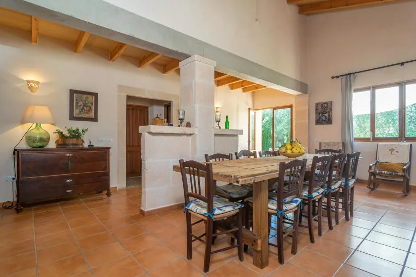 Comedor con una mesa larga de madera y sillas bajo vigas de techo expuestas.
