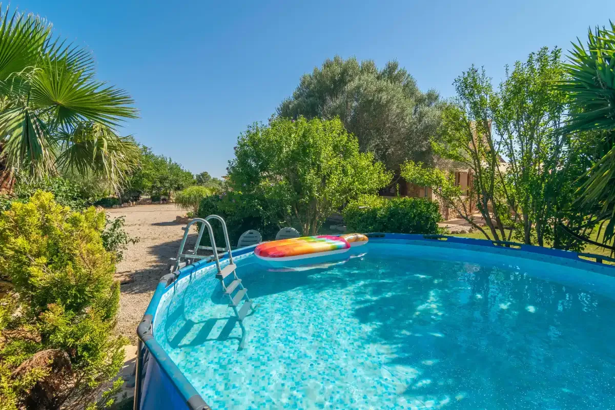 Una piscina al aire libre rodeada de vegetación y árboles.