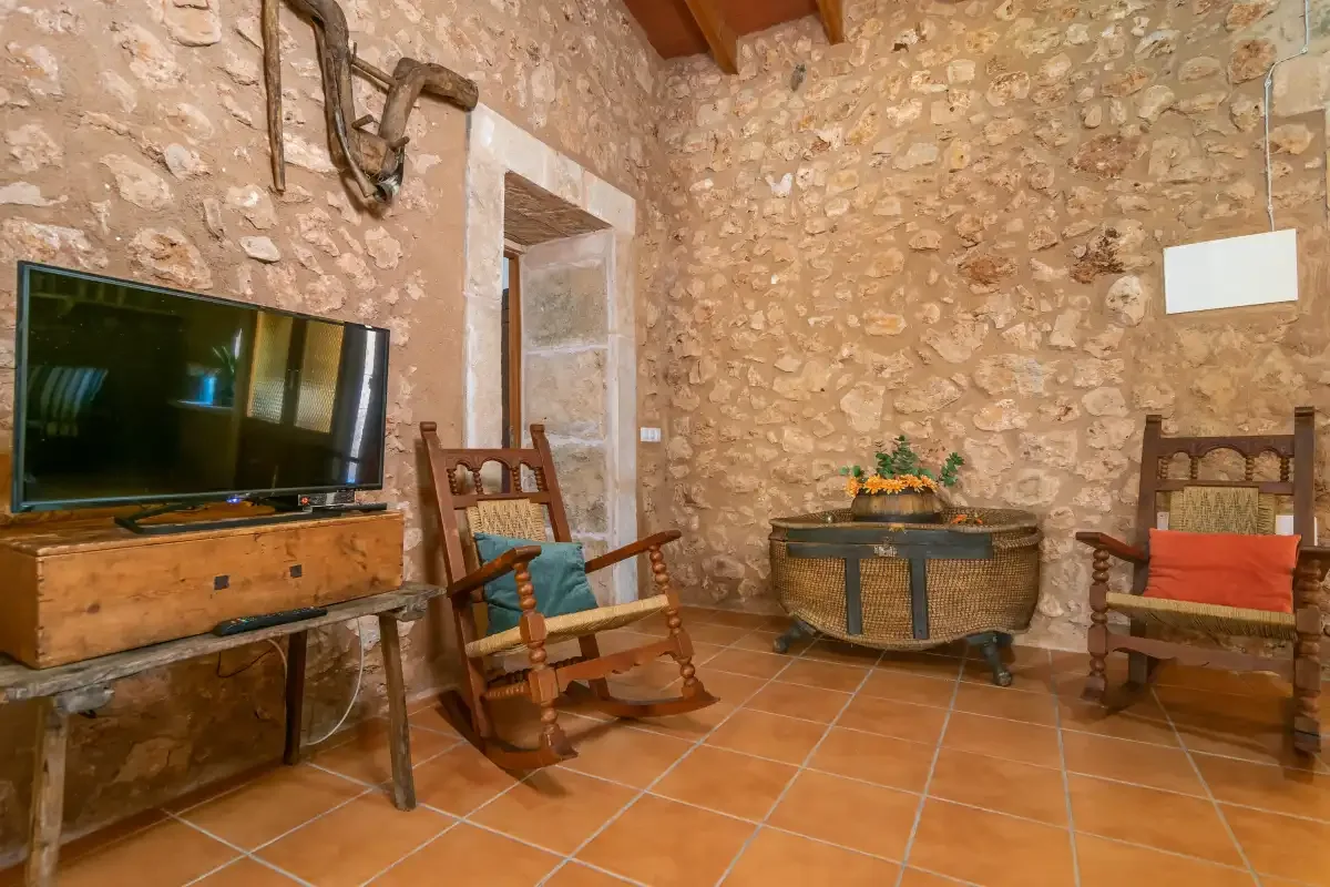Una sala de estar de piedra con asientos de madera y un televisor.