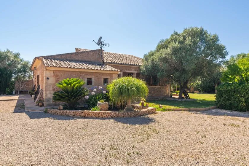 Una casa con techo de tejas se encuentra junto a un patio de grava y un jardín.