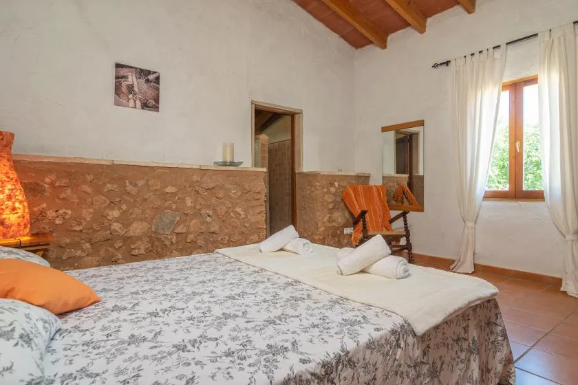 Un dormitorio con dos camas, una ventana con cortinas y vigas de madera a la vista.