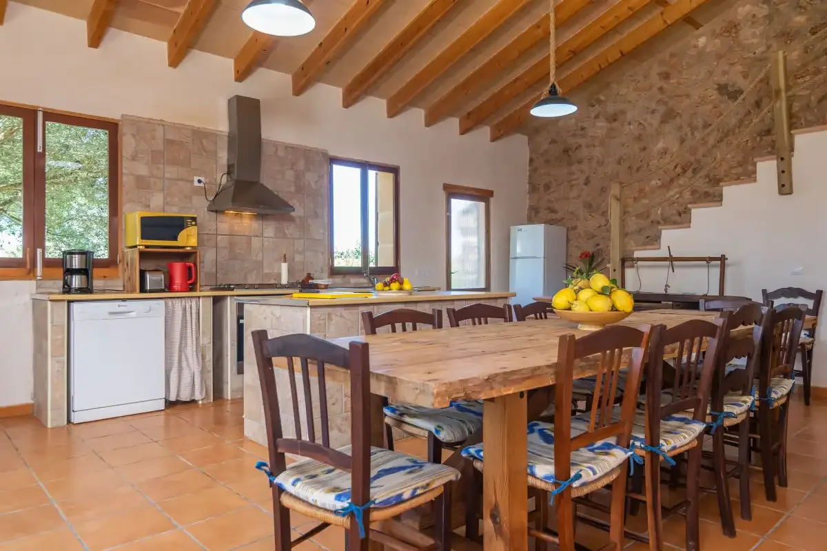 Una cocina y comedor rústicos con una larga mesa de madera y vigas vistas.