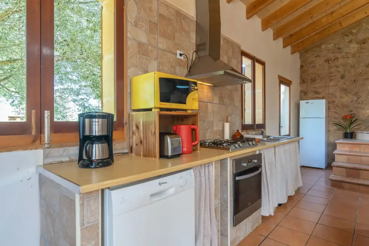 Una cocina rústica con una encimera larga, horno integrado y refrigerador.