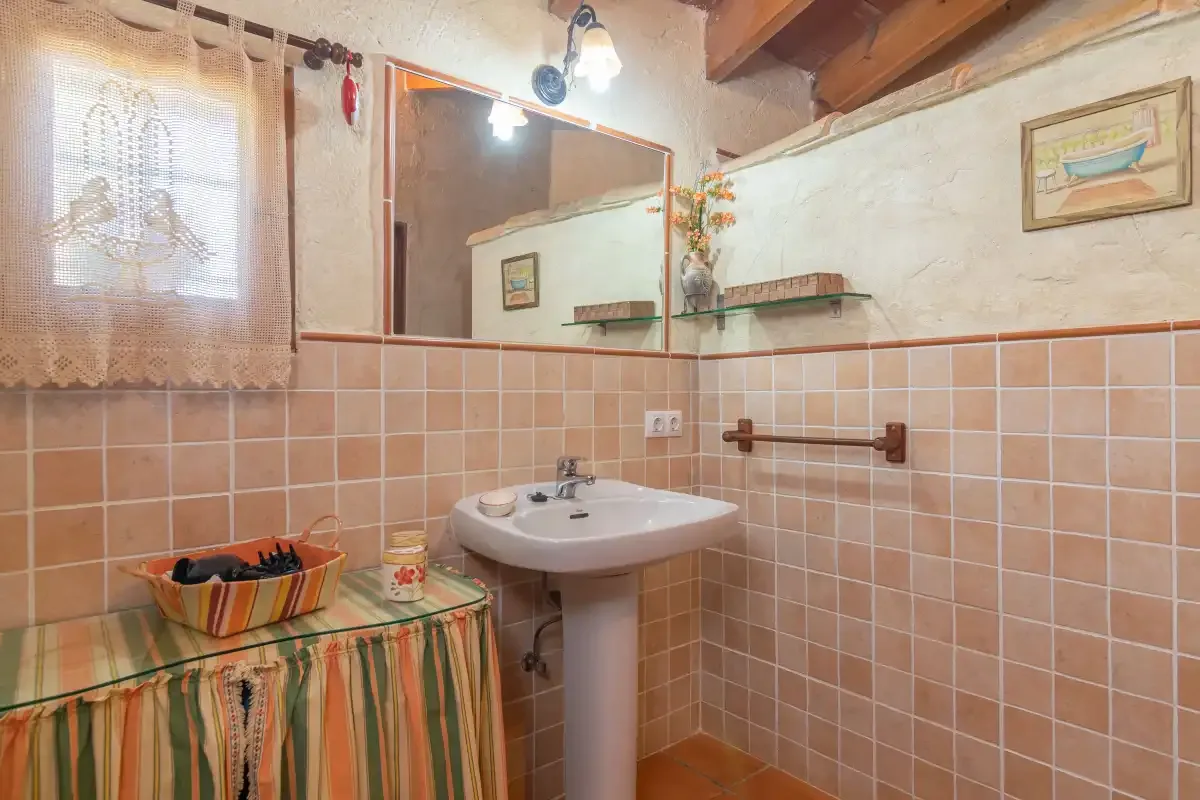 Un baño con azulejos, lavabo con pedestal y espejo.