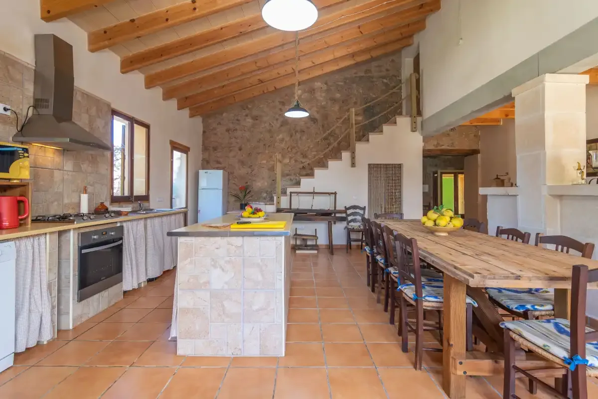 Una amplia cocina y zona de comedor con una mesa larga de madera y una isla central.