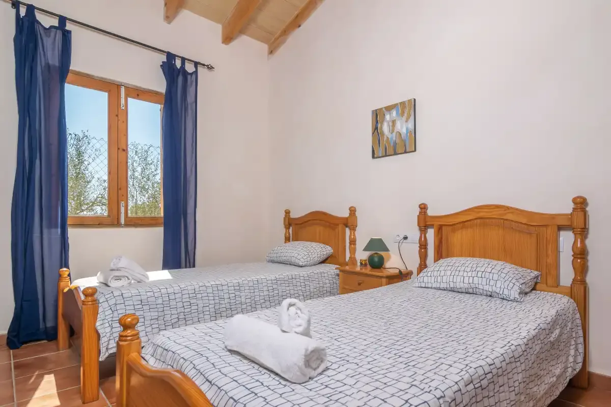 Un dormitorio con dos camas, cortinas azules y techo de madera.