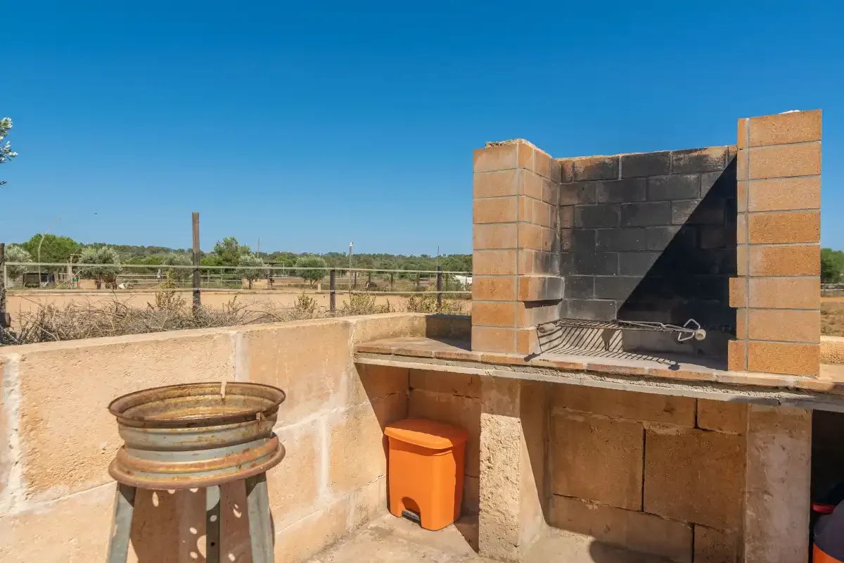 Una zona de cocina al aire libre con una parrilla y una estufa cilíndrica de metal.
