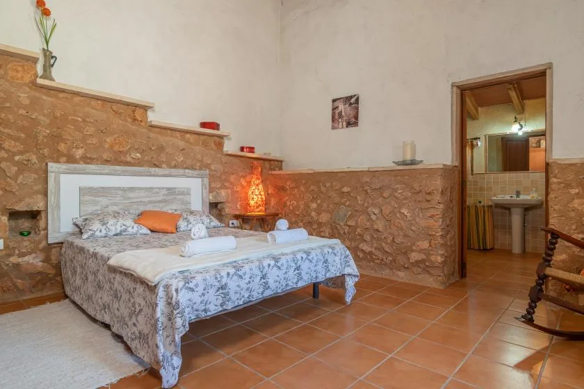 Un dormitorio con una cama estampada y una puerta abierta hacia un baño.