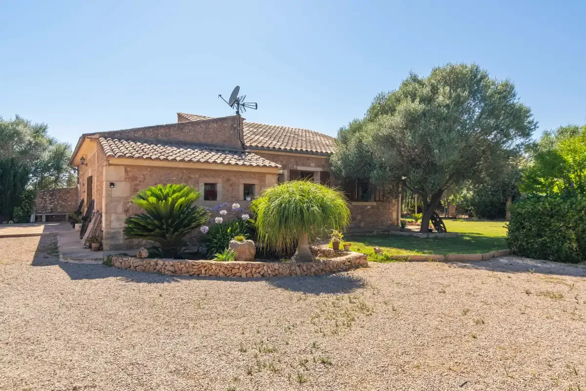 Una casa con tejado de tejas se encuentra junto a un camino de grava y un jardín ajardinado.