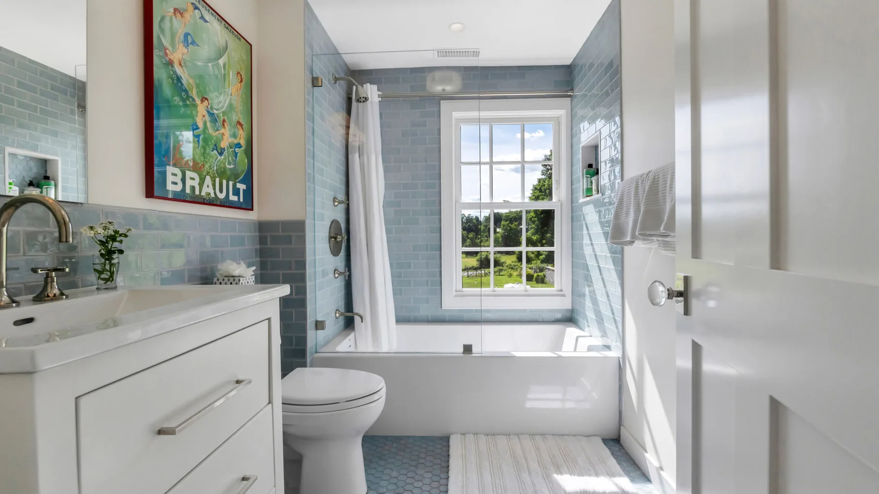 A bright bathroom with a bathtub beneath a window and a white vanity.