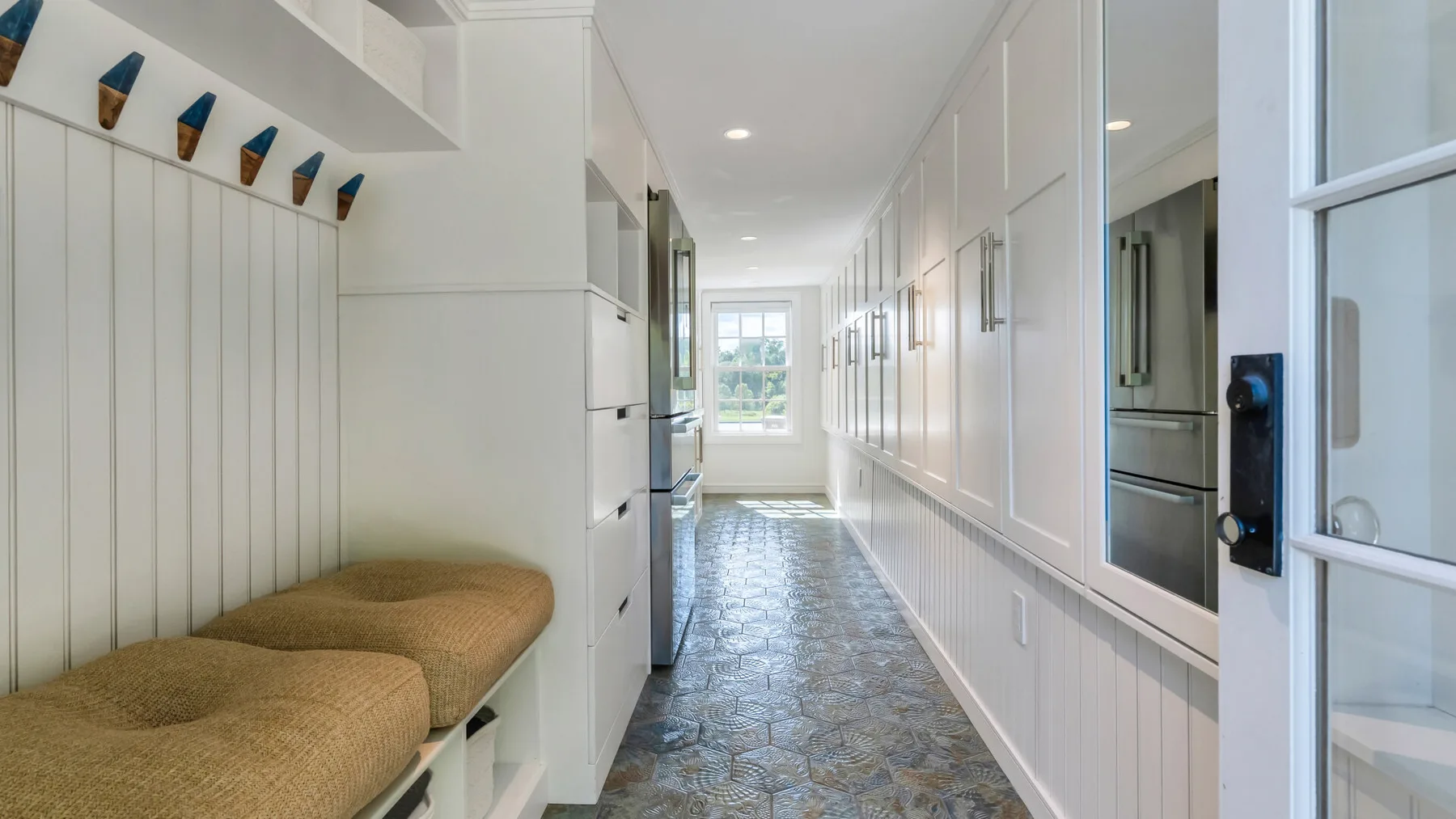 A bright, narrow hallway with built-in seating and patterned tile flooring.