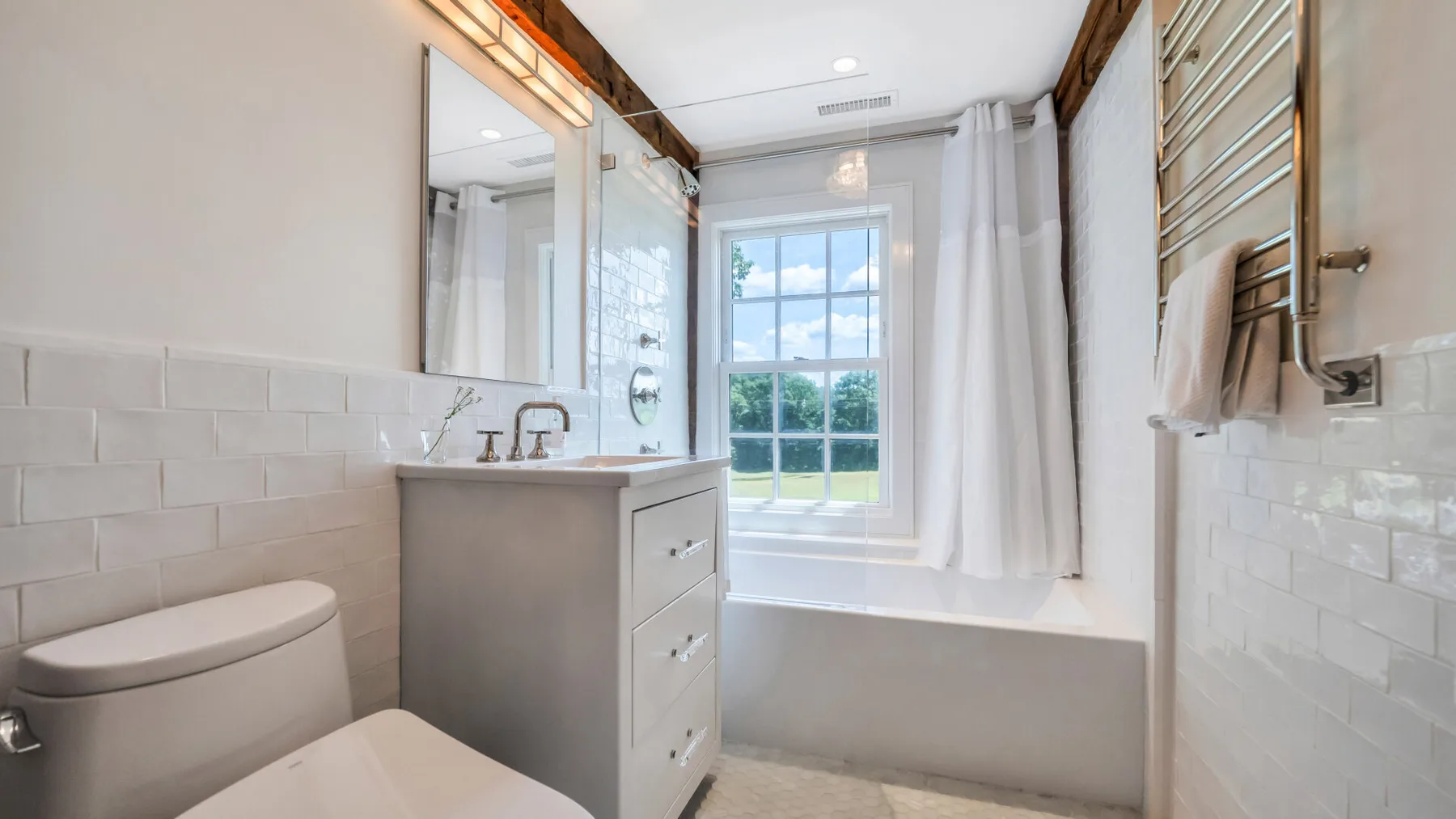 A bright bathroom with a bathtub, vanity, and window.
