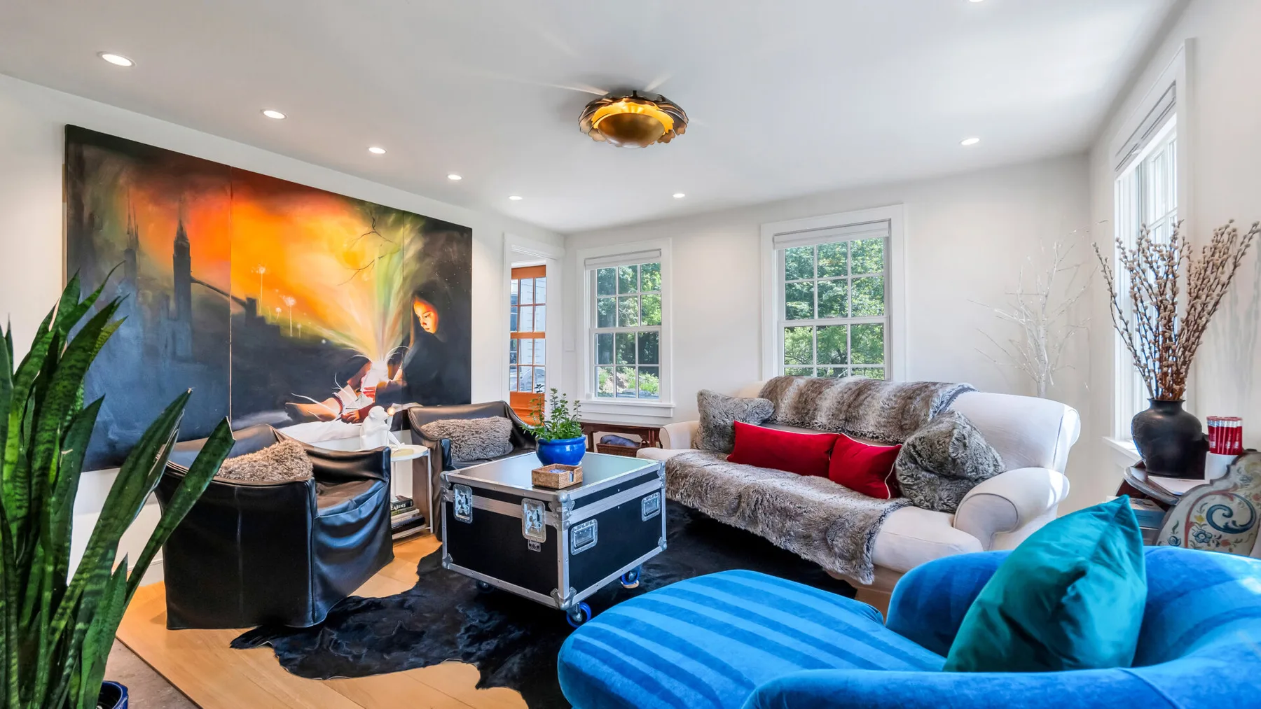 A bright living room features seating, a coffee table, and colorful wall art.
