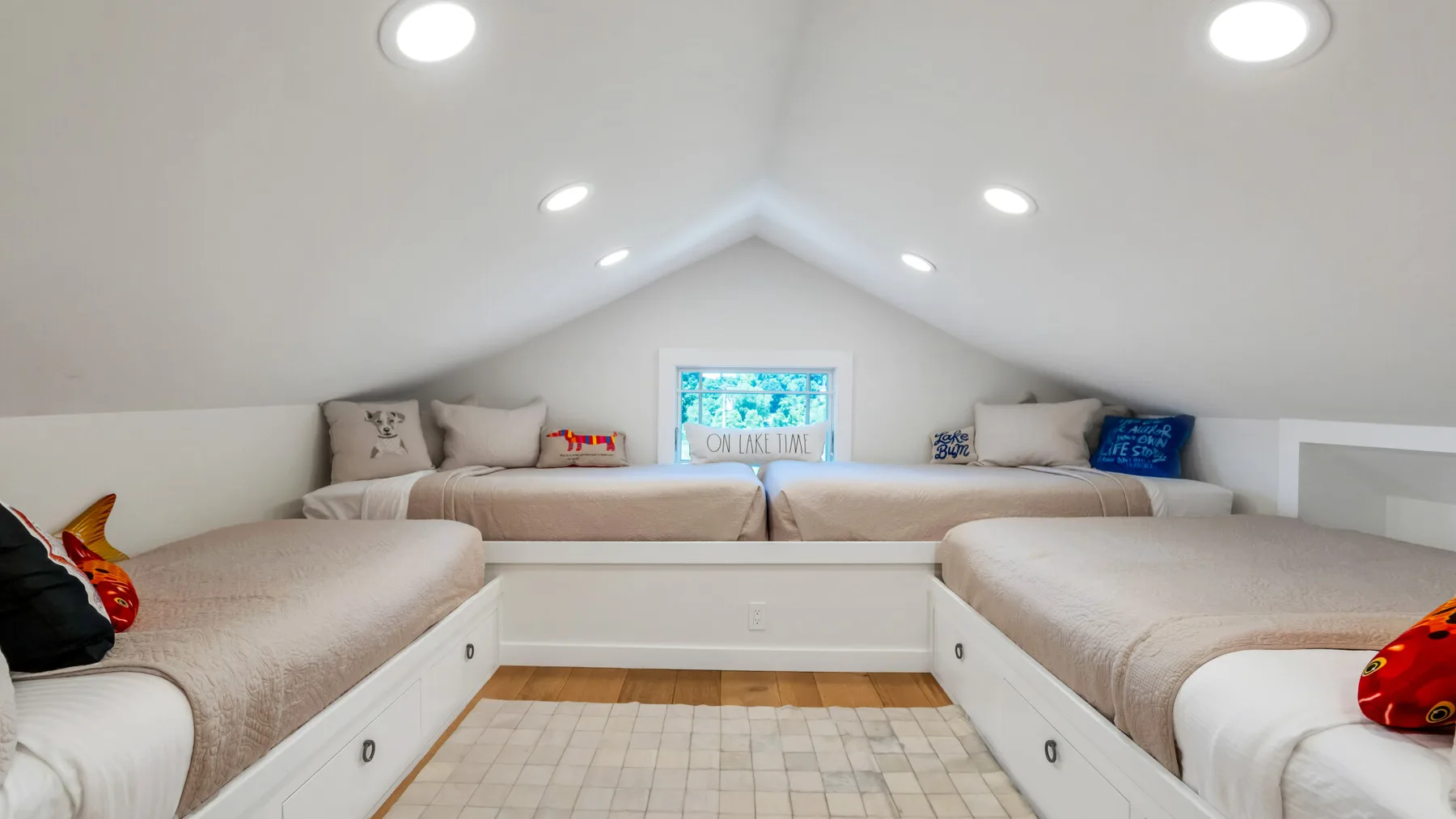 A bright attic bedroom with beds arranged around a central tiled floor.
