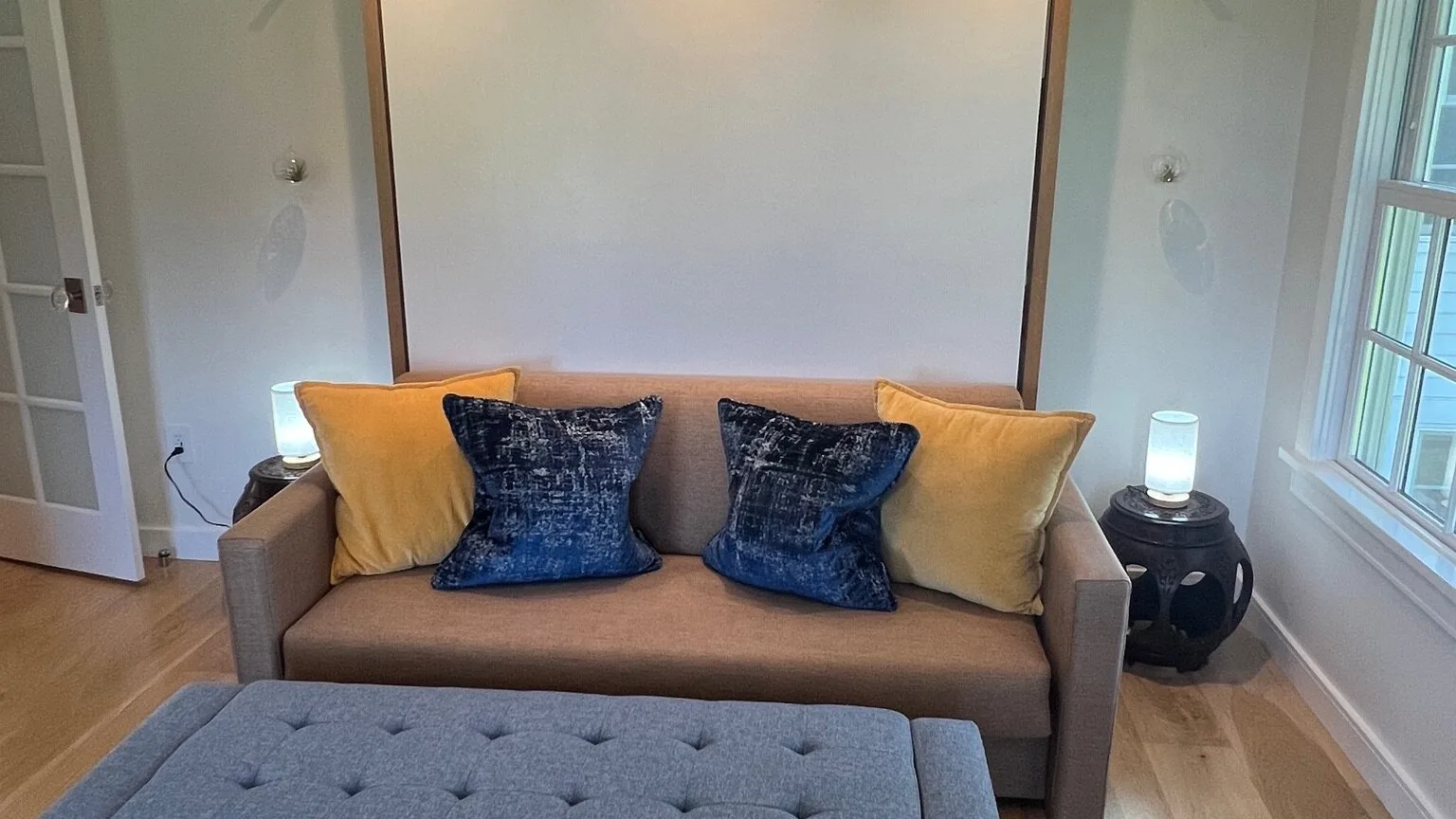 A living room with a sofa and blue cushions beside a window.