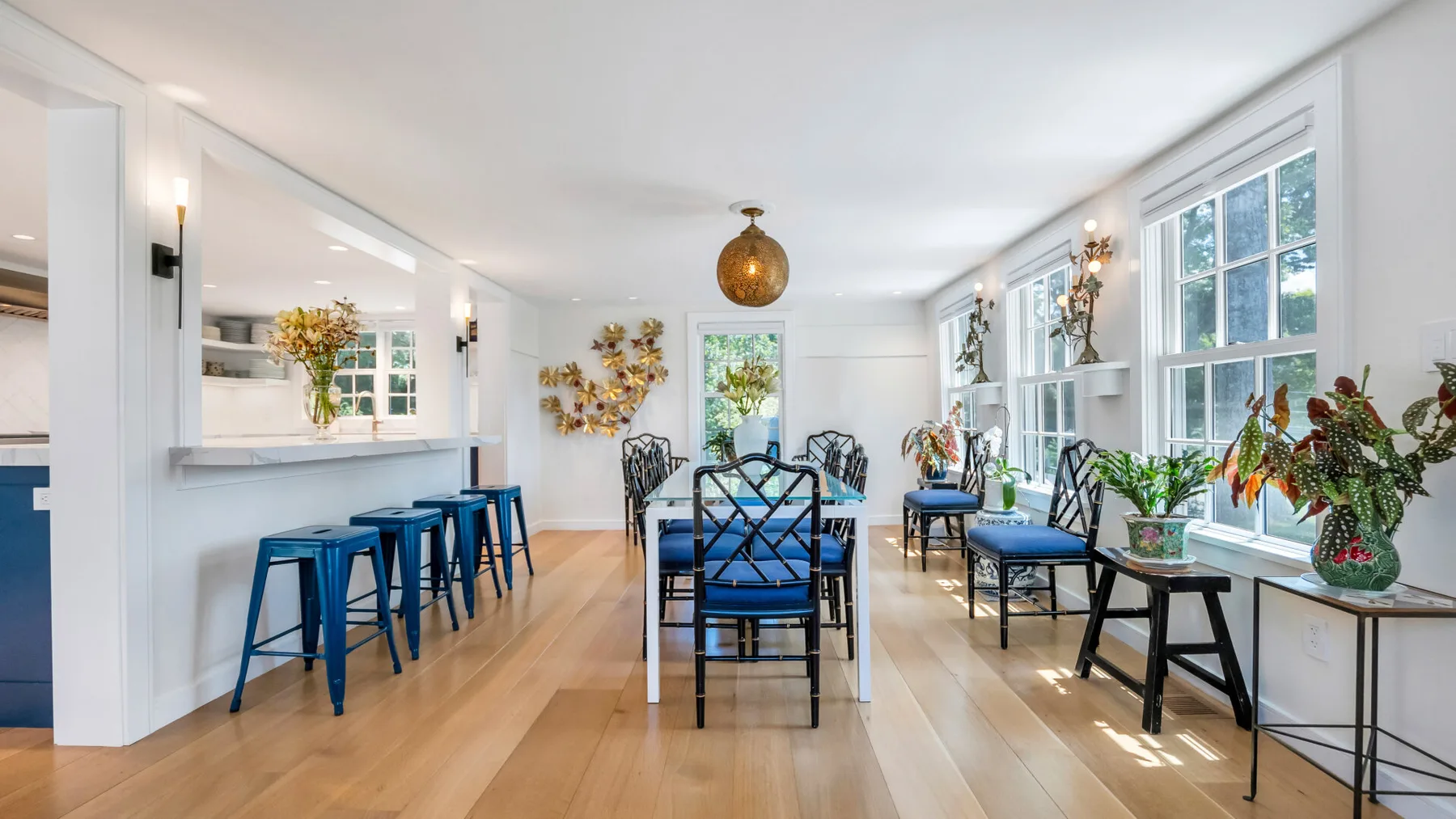 A bright dining room with a long table and blue seating beside large windows.