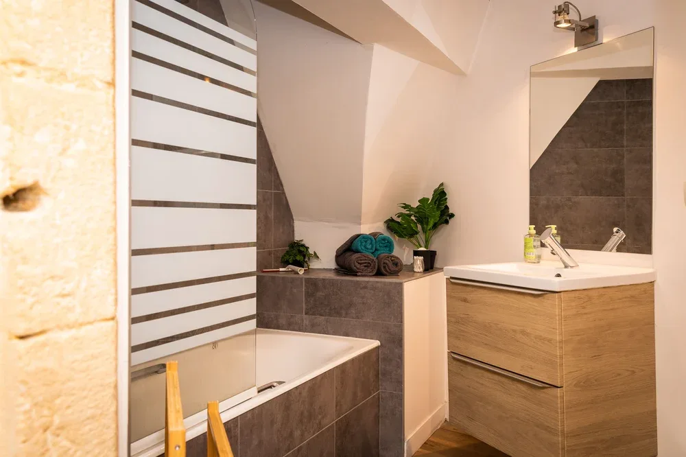 A bathroom with a bathtub and a wood-front vanity.