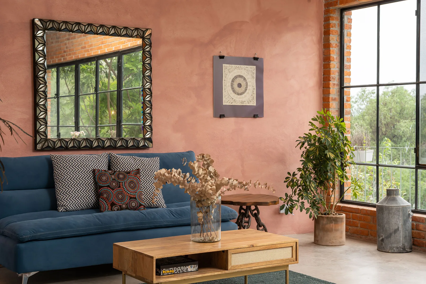 A living room with blue seating, a wooden coffee table, and large windows.
