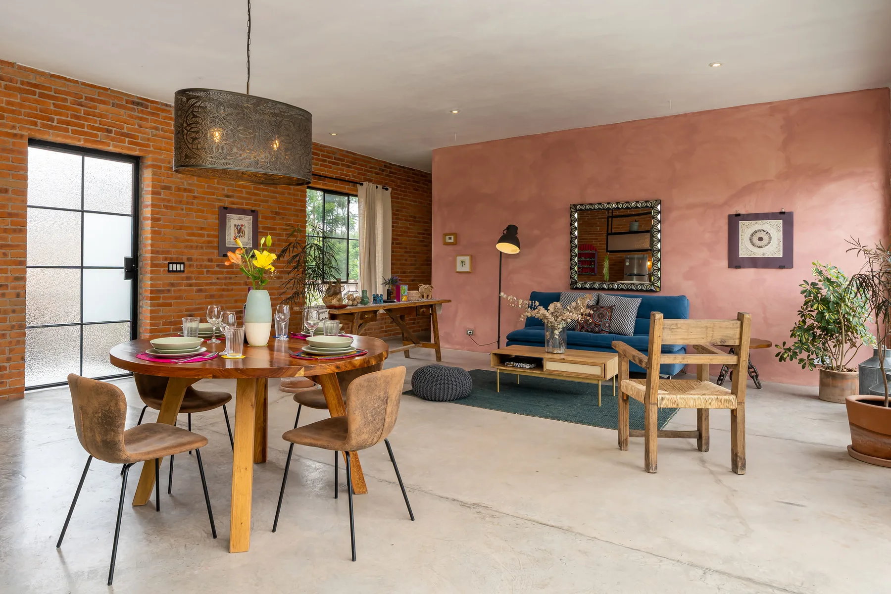 A dining and seating area features a table, blue sofa, and brick wall.