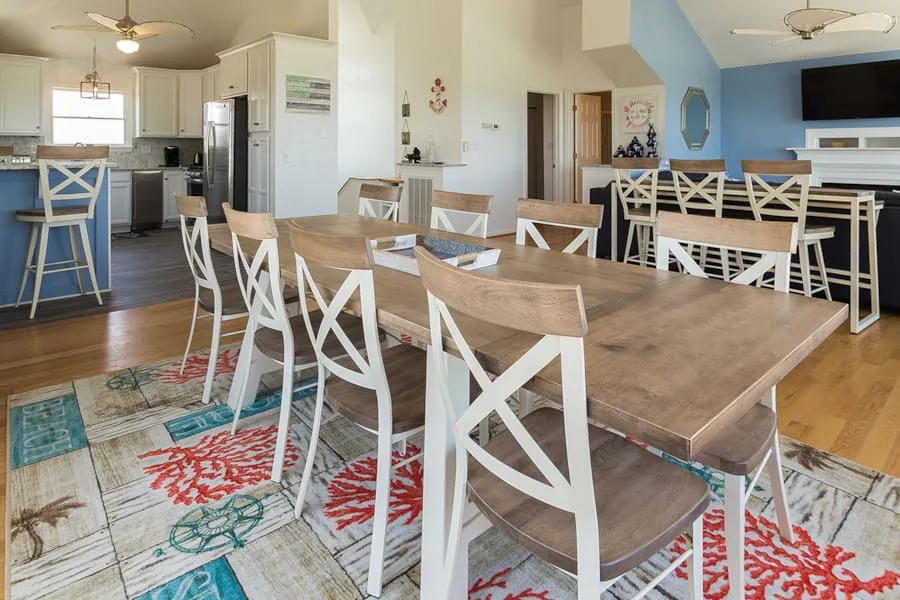 Comedor con mesas de madera y asientos blancos con respaldos cruzados.