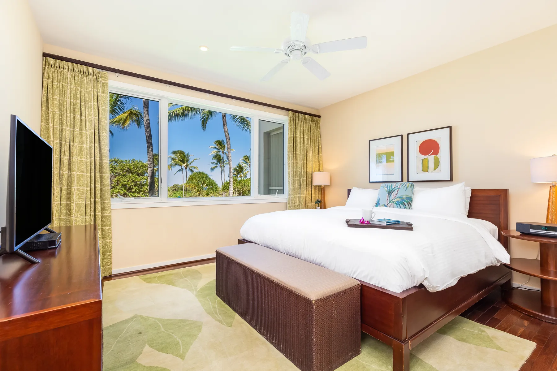 Un dormitorio luminoso con una cama grande y ventanas con vistas a palmeras.