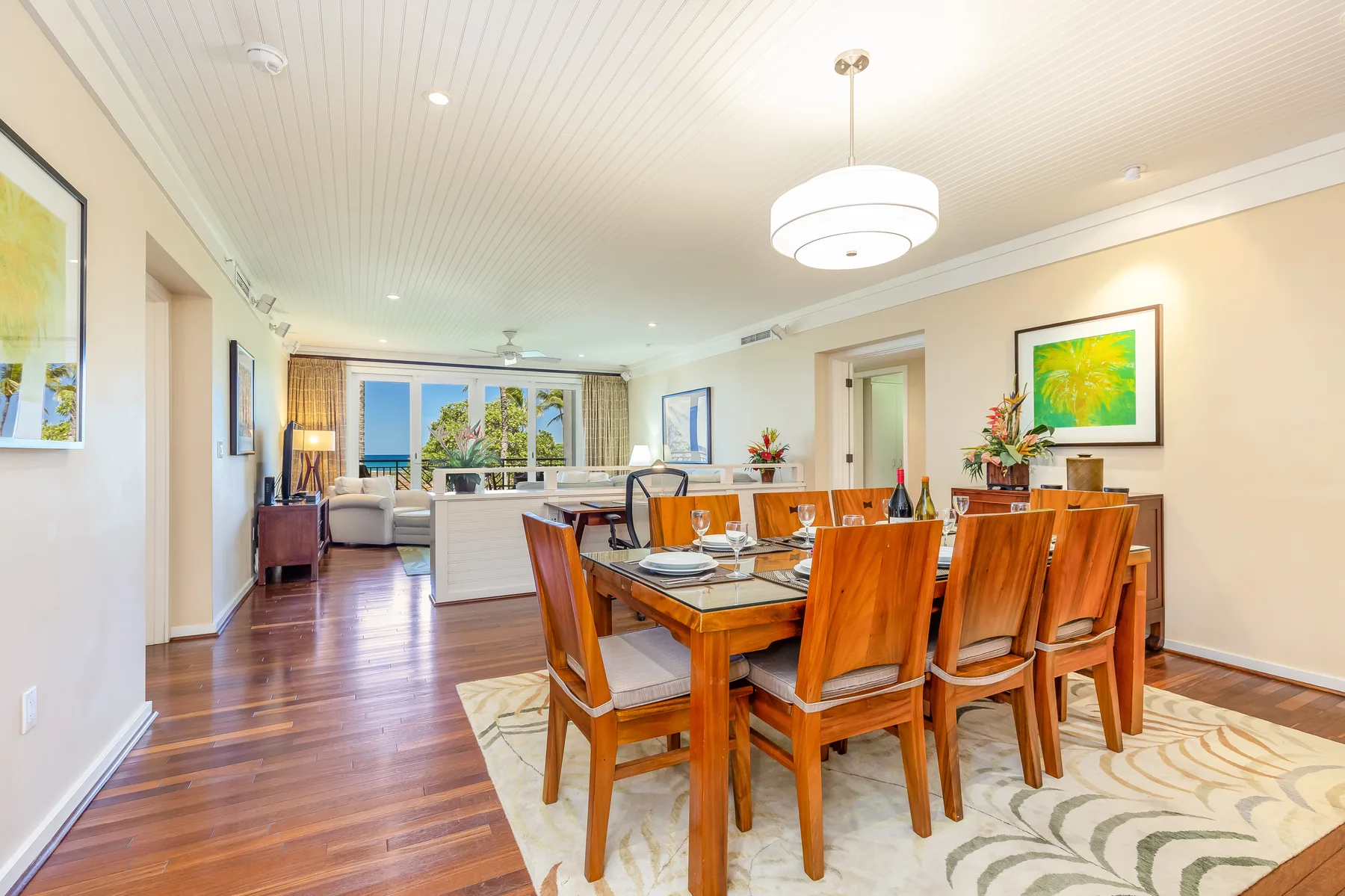Comedor con una mesa de madera y sillas junto a una sala de estar luminosa.