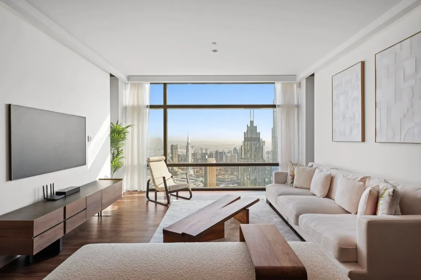 A bright living room with a sofa and floor-to-ceiling windows overlooking the city.
