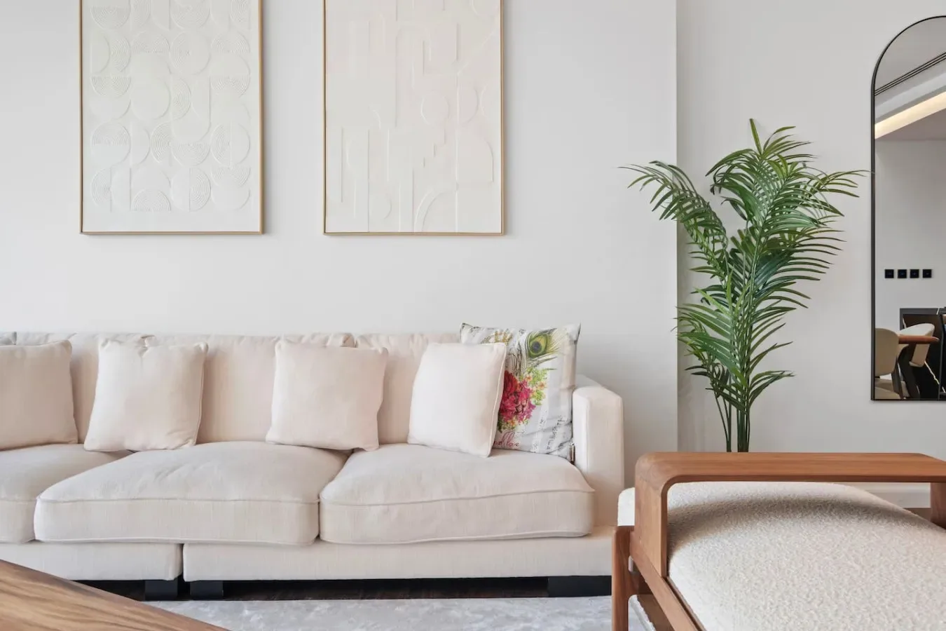 A bright living room with a light-colored sofa and a leafy plant.