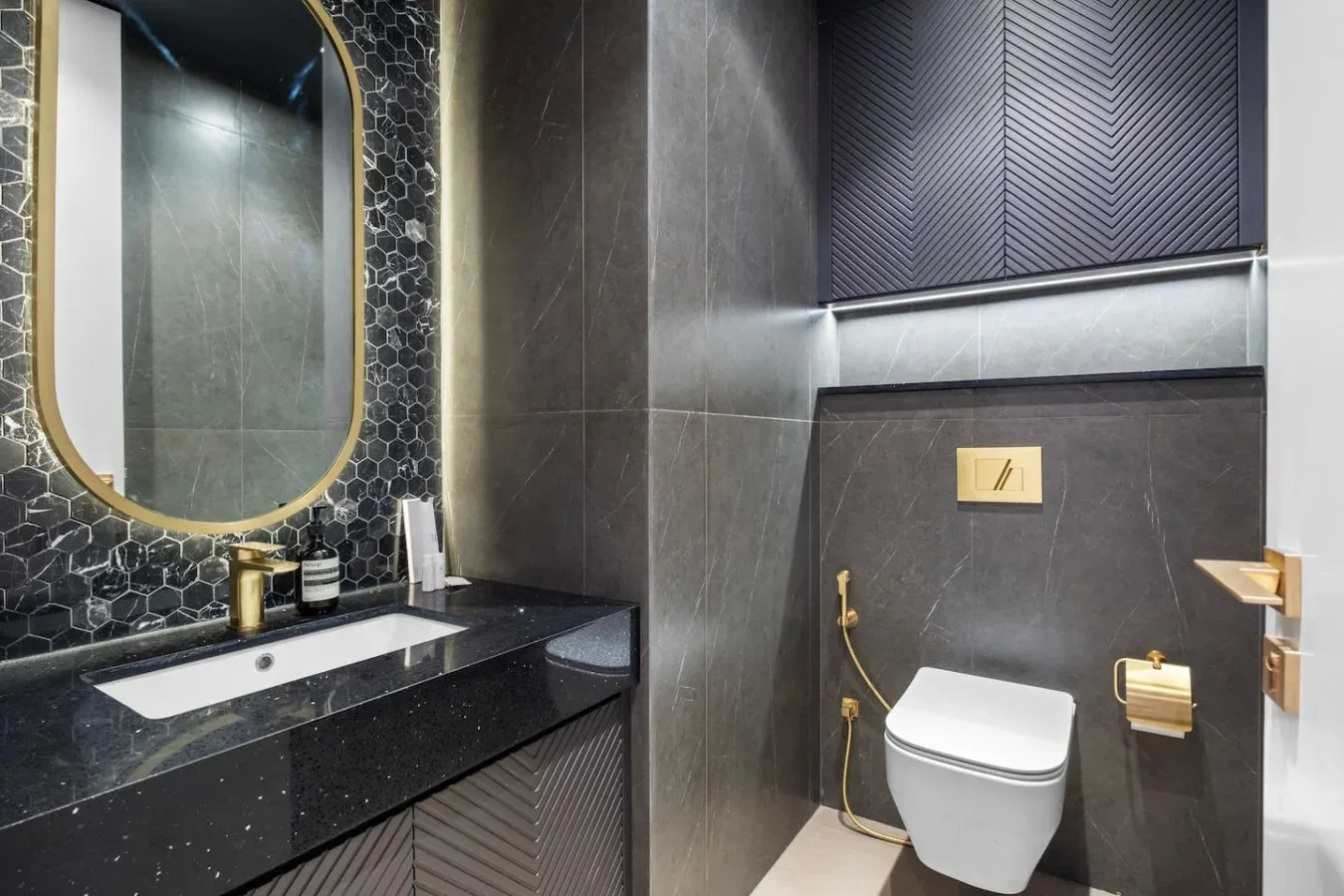 A modern bathroom with a dark vanity, mirror, and toilet.
