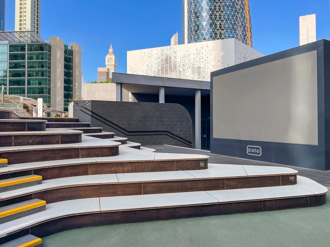 Outdoor urban plaza with broad curved steps and modern buildings in the background.