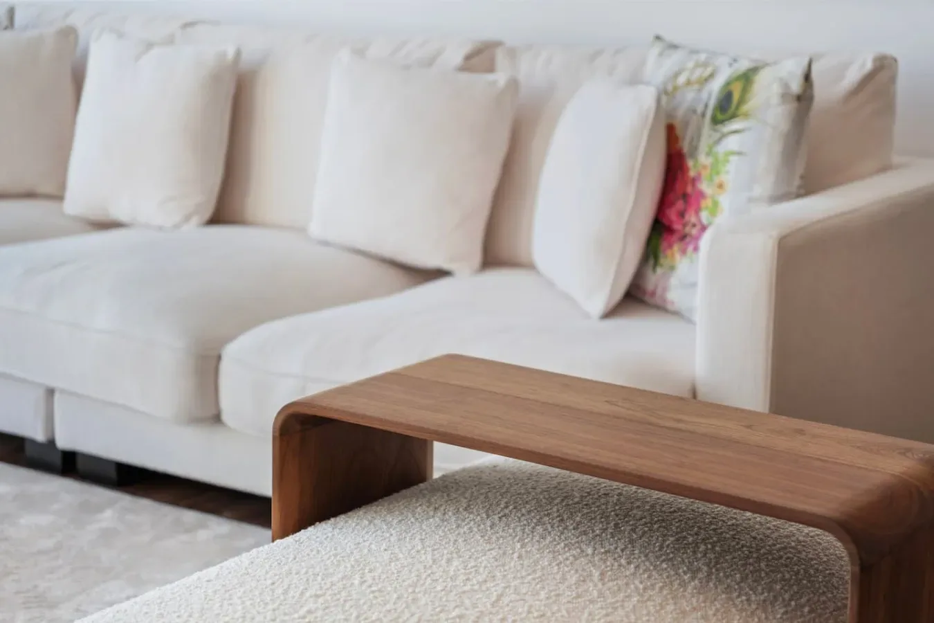 A bright living room with a white sofa and a wooden coffee table.