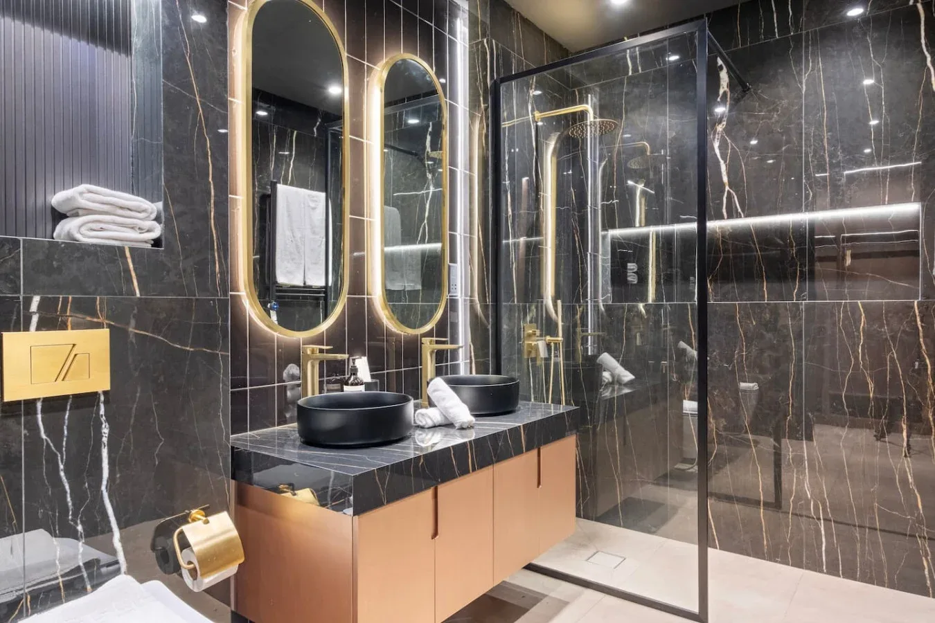 A modern bathroom with a vanity, illuminated mirrors, and a glass shower.